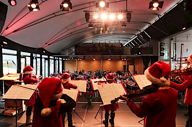Geige spielende Kinder mit Nikolausmützen auf der Bühne des PUC Geige spielende Kinder mit Nikolausmützen auf der Bühne des PUC
